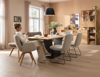 Geteilte Ansicht mit Essbereich links und Wohnzimmer rechts, Holzmöbel, Sofa, Couchtisch und Regal sowie große Fenster im Raum
